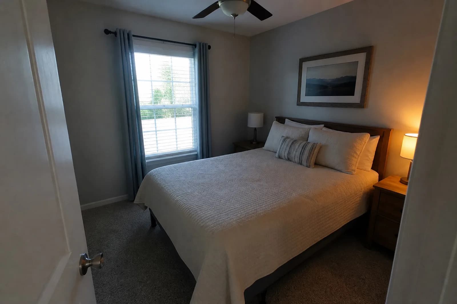 Original guest bedroom photo with a bright window and mixed lamp color
